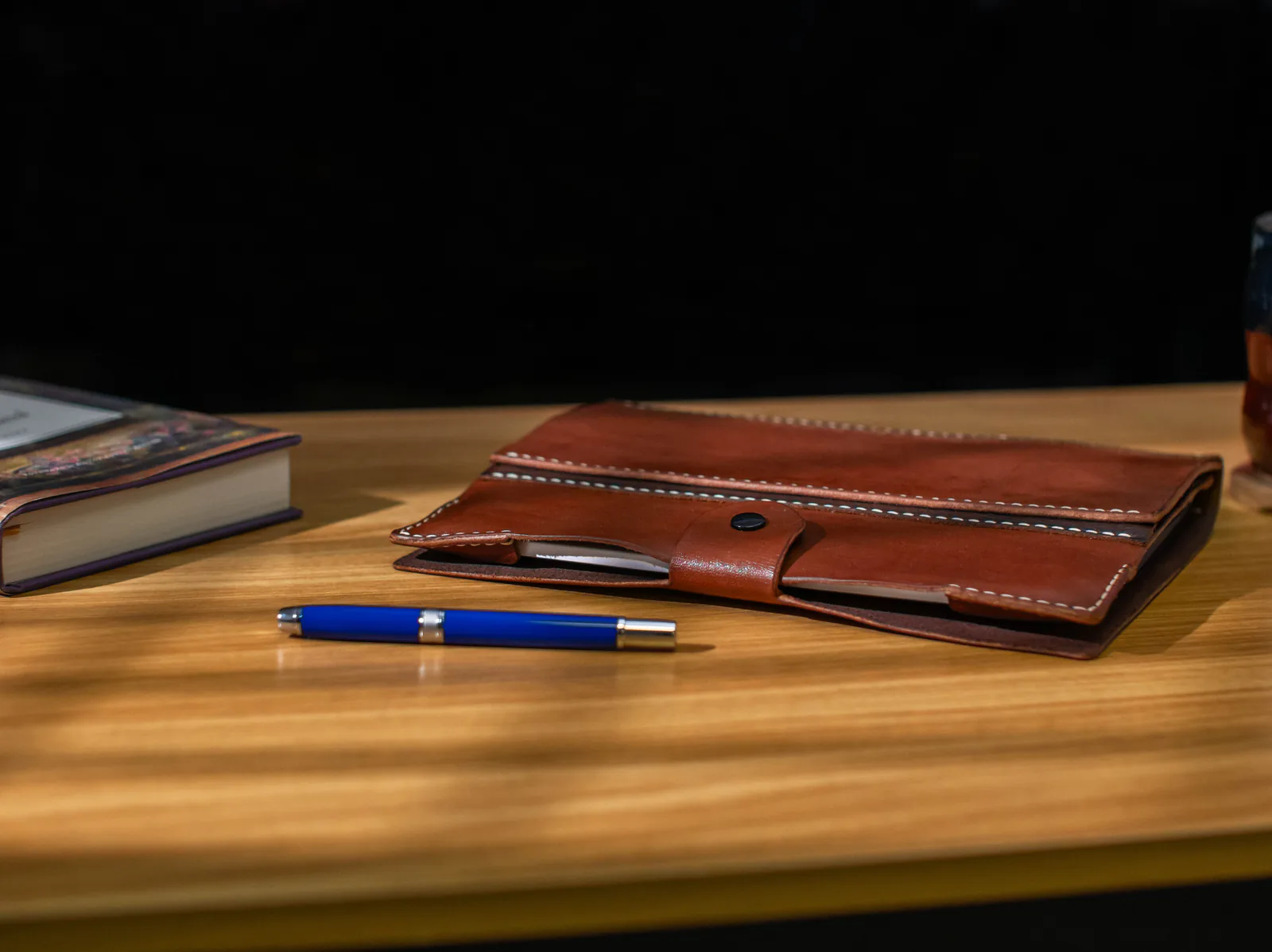 The Bookish leather folio resting beside a fountain pen and book