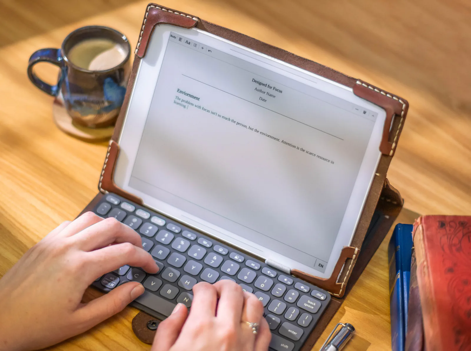 Hands typing on the Bookish keyboard beside the E-Paper workspace