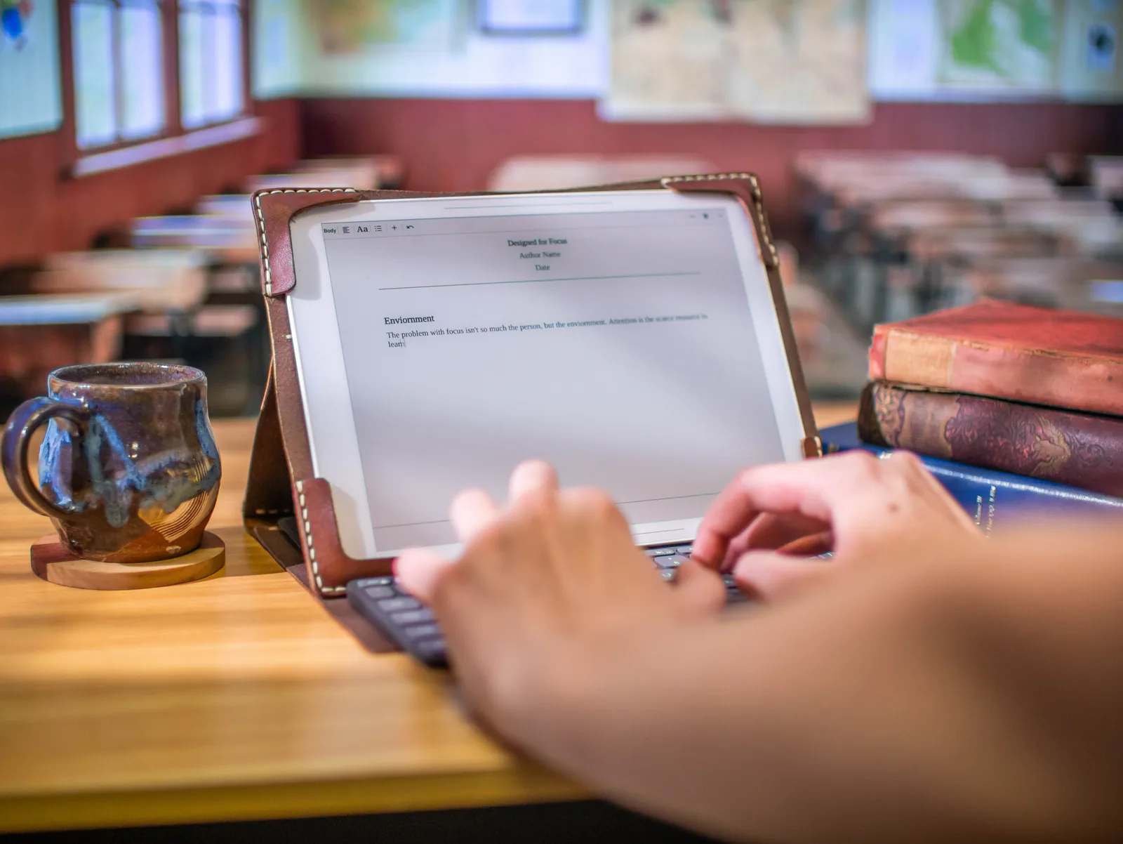 Hands typing on Bookish with a classroom behind
